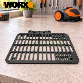 Black XL slotted plastic plate for robotic mower on workshop bench